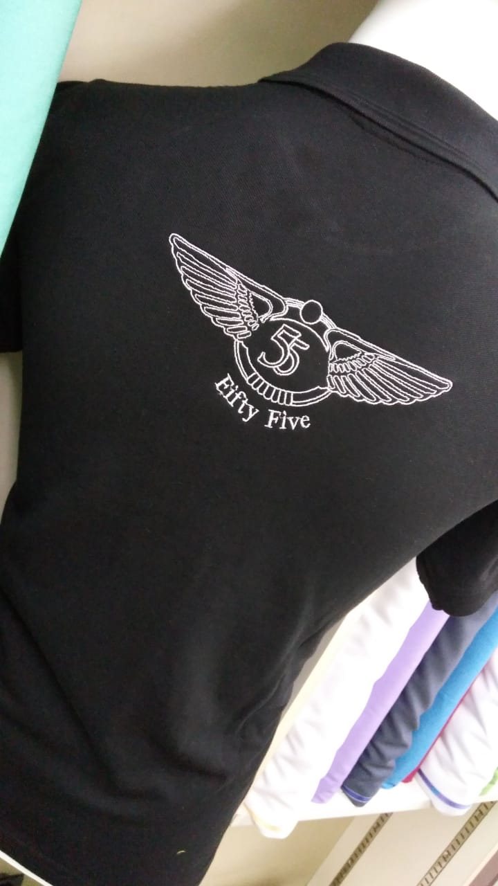 Back of a black polo shirt with a white embroidered winged emblem