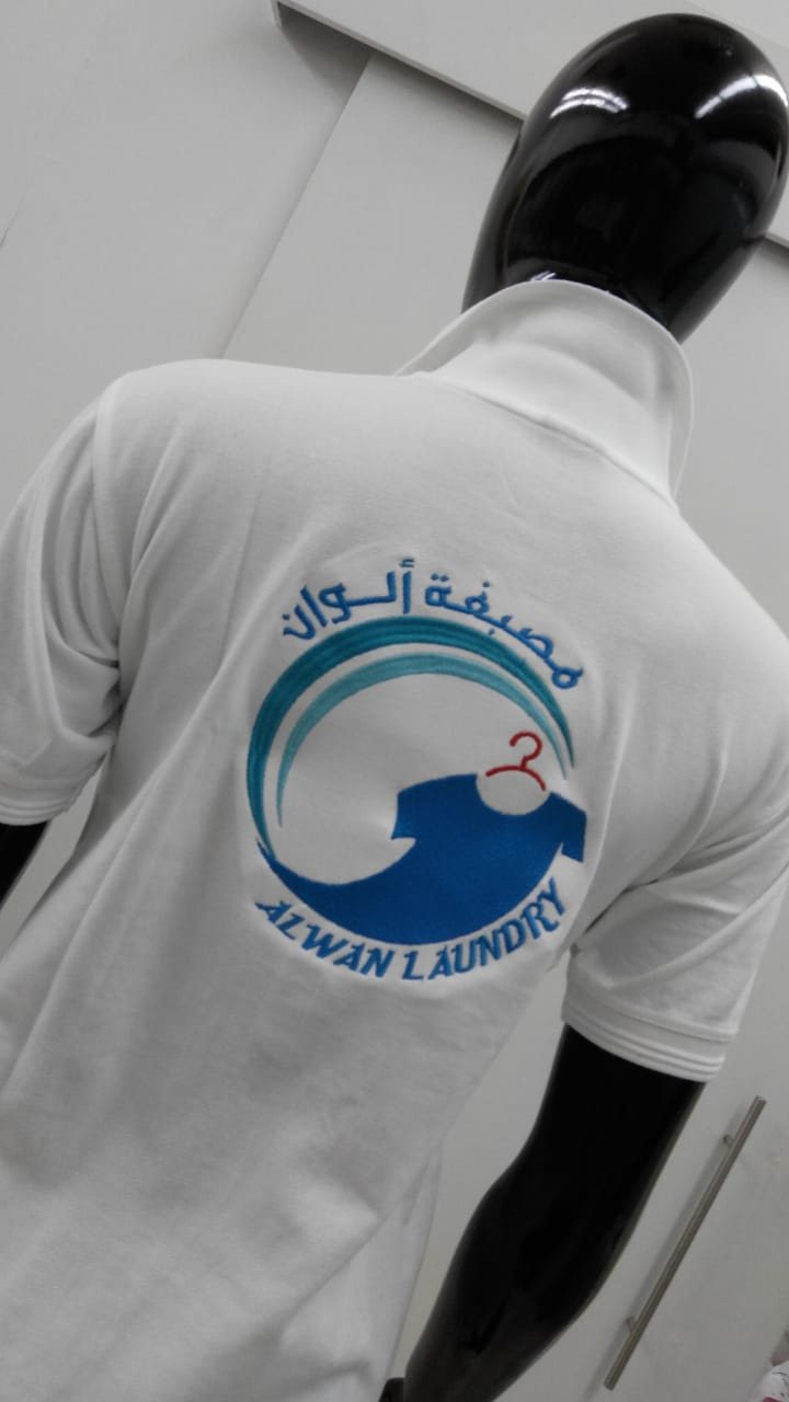 White polo shirt with a printed blue wave logo and Arabic text on the back, on a mannequin