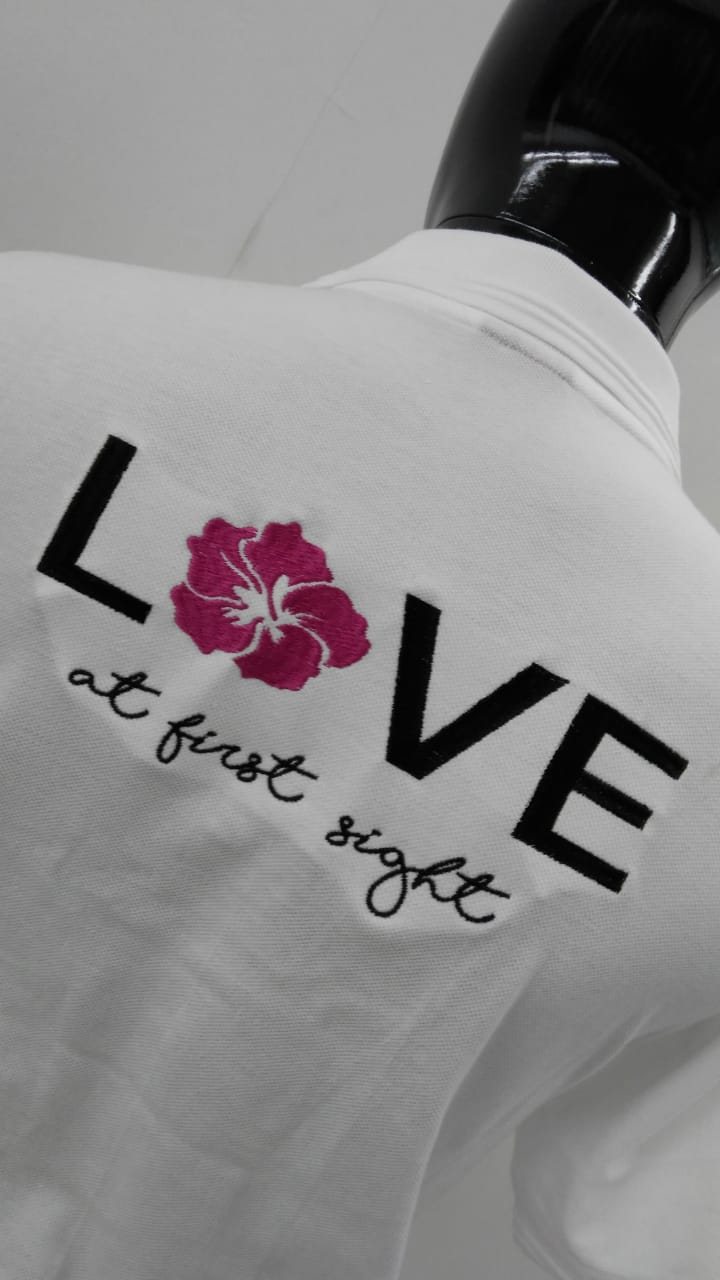 White T-shirt printed with 'LOVE at first sight' and a pink hibiscus in place of the O