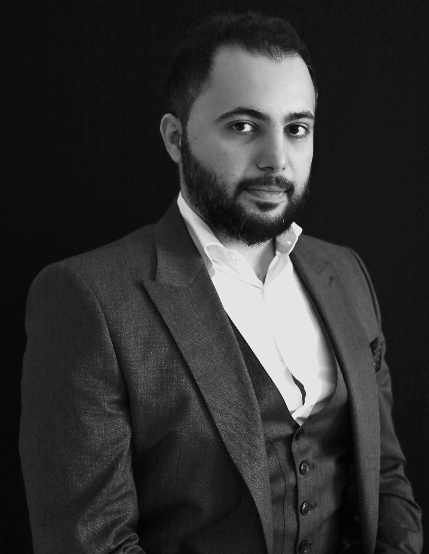 Black-and-white portrait of Hadi Hijazi of Gravity Uniforms in a dark suit jacket